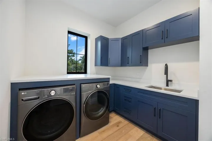 Washroom featuring light wood-type flooring, independent washer and dryer, and cabinet space