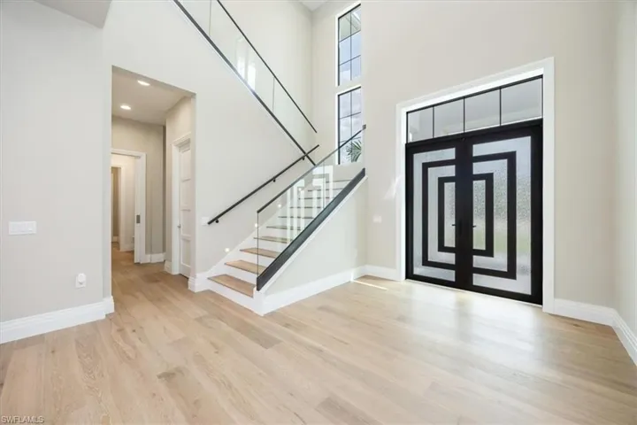 Foyer with a towering ceiling, light wood-style floors, stairway, and recessed lighting