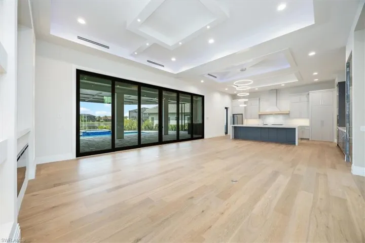 Unfurnished living room featuring a raised ceiling, light wood finished floors, recessed lighting, and a fireplace