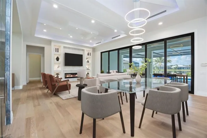Dining area with a tray ceiling, light wood finished floors, a fireplace, recessed lighting, and built in features