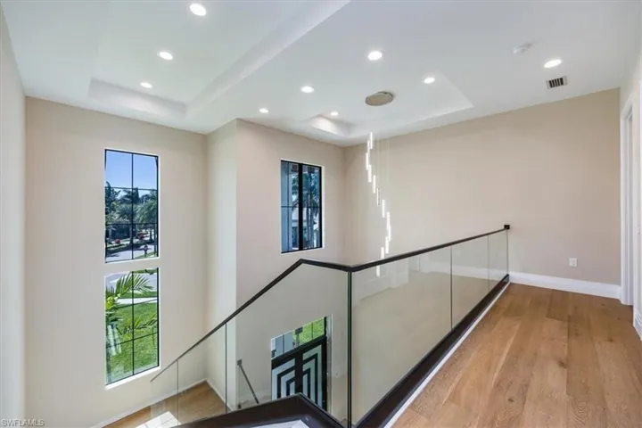 Corridor featuring a raised ceiling, light wood-style floors, and recessed lighting