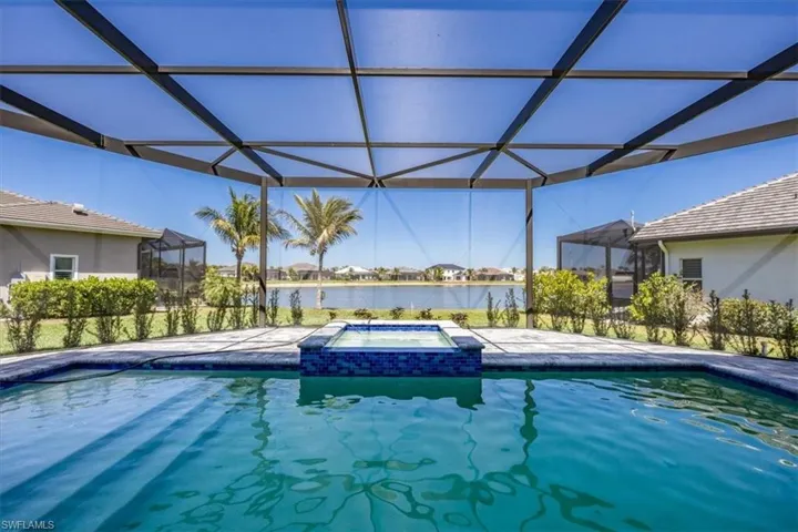 View of pool featuring a sunroom, a pool with connected hot tub, a water view, a residential view, and a patio area