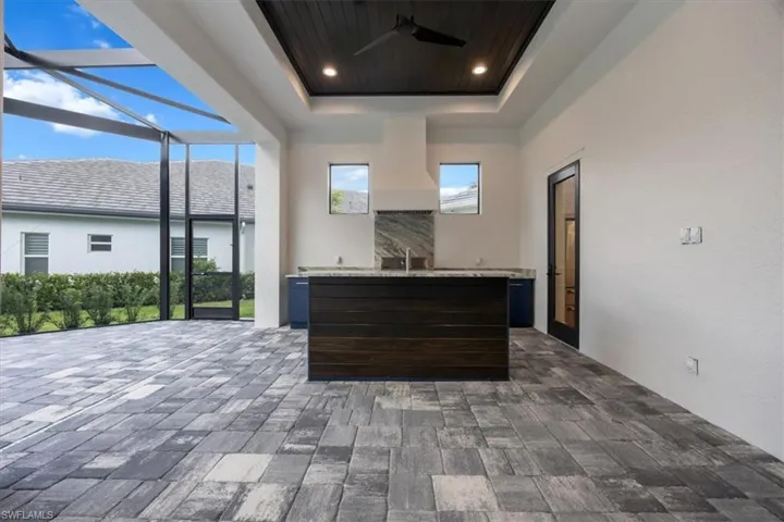 Kitchen with dark brown cabinets, a tray ceiling, recessed lighting, ceiling fan, and a kitchen island with sink