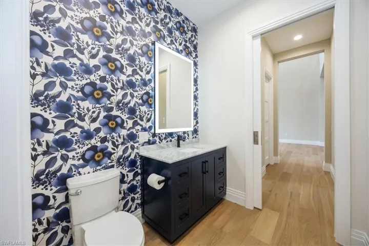 Bathroom featuring light wood finished floors, vanity, recessed lighting, and wallpapered walls