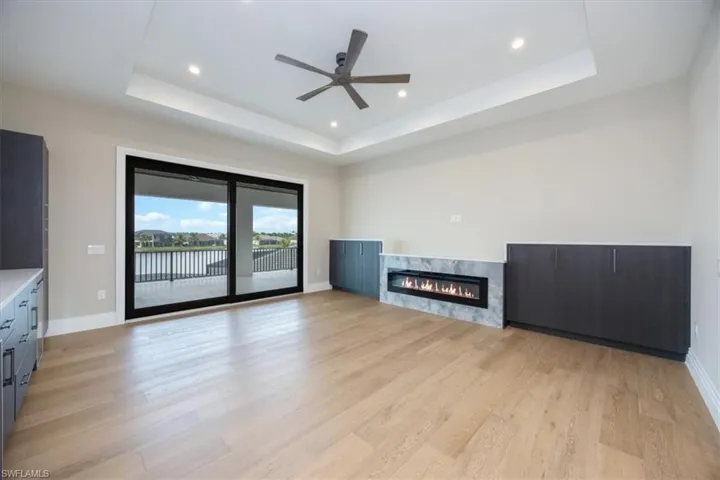 Unfurnished living room with a raised ceiling, recessed lighting, light wood-style floors, and a high end fireplace