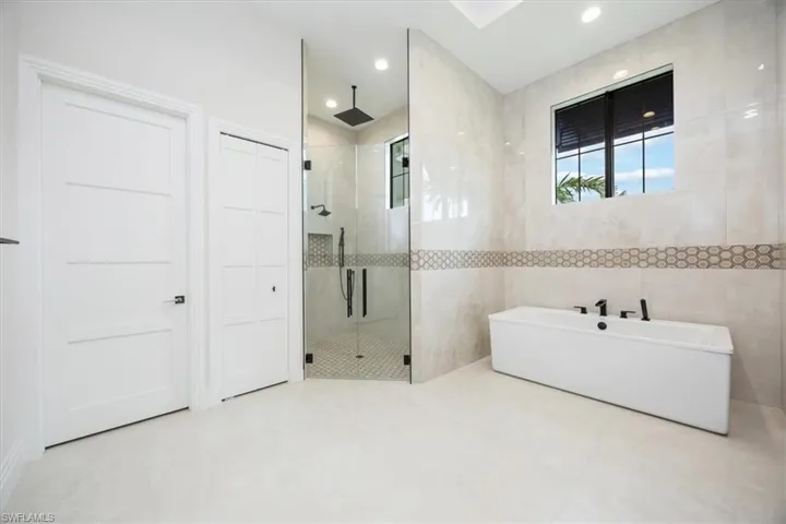 Full bathroom featuring tile walls, a shower stall, a freestanding bath, and recessed lighting
