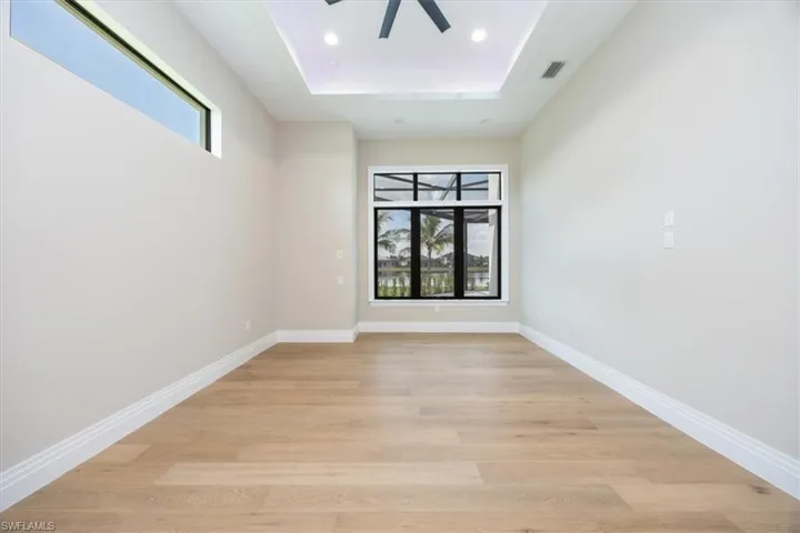Spare room featuring a tray ceiling, light wood finished floors, ceiling fan, and recessed lighting