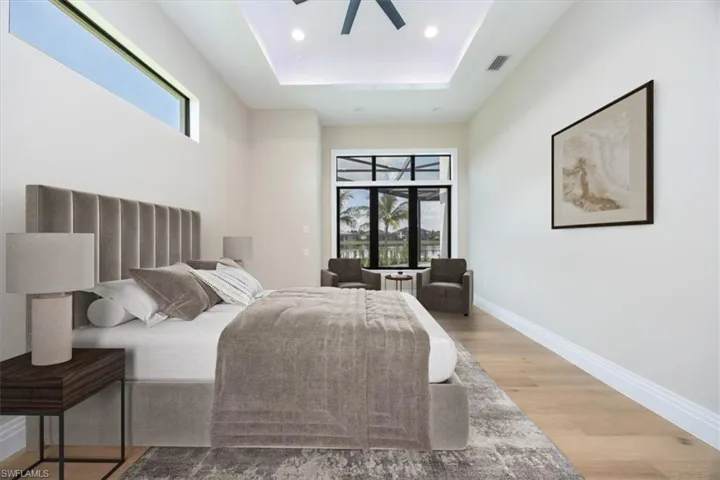 Bedroom featuring wood finished floors, a raised ceiling, recessed lighting, and a ceiling fan