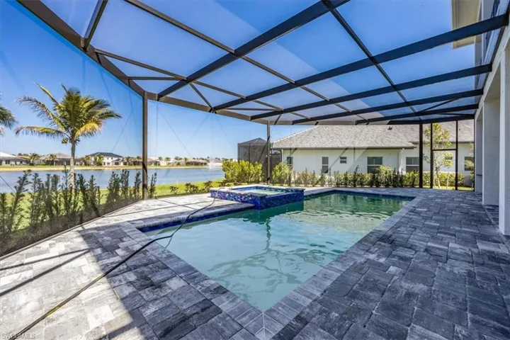 View of pool with a sunroom, a lanai, a water view, a pool with connected hot tub, and a patio area