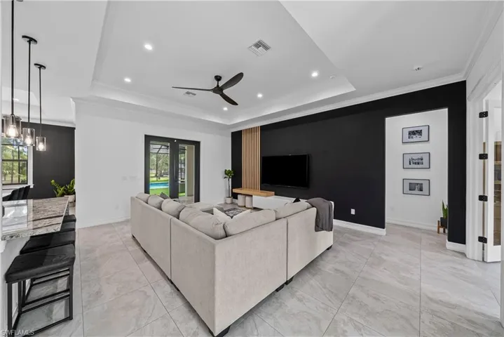 Living room featuring ornamental molding, ceiling fan, a raised ceiling, and recessed lighting