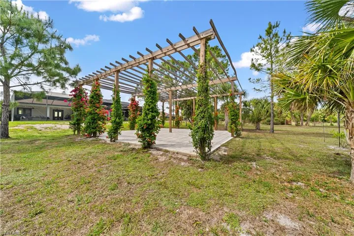 View of grassy yard featuring a pergola and a patio