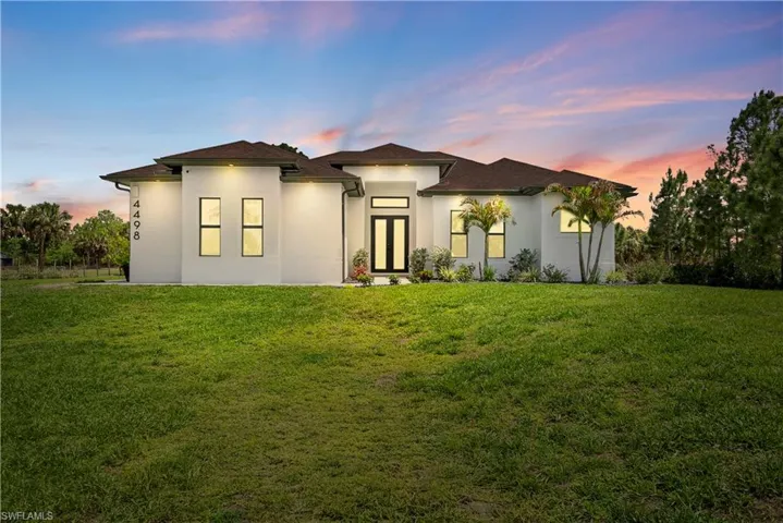 View of front facade featuring stucco siding and a lawn