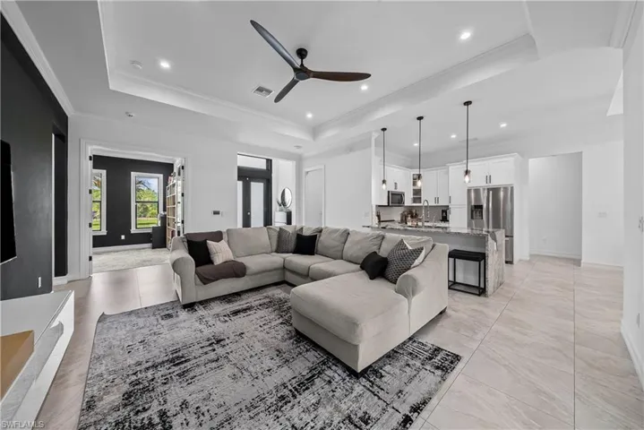 Living area featuring ceiling fan, crown molding, a tray ceiling, and recessed lighting