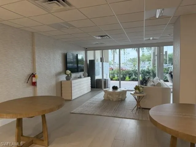 Open-concept interior featuring wood-finish flooring, textured wall coverings, and abundant natural light through floor-to-ceiling windows