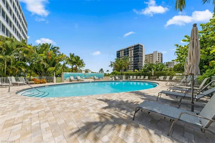 Resort-style pool area featuring a curved swimming pool, integrated entry steps, and a surrounding paver patio