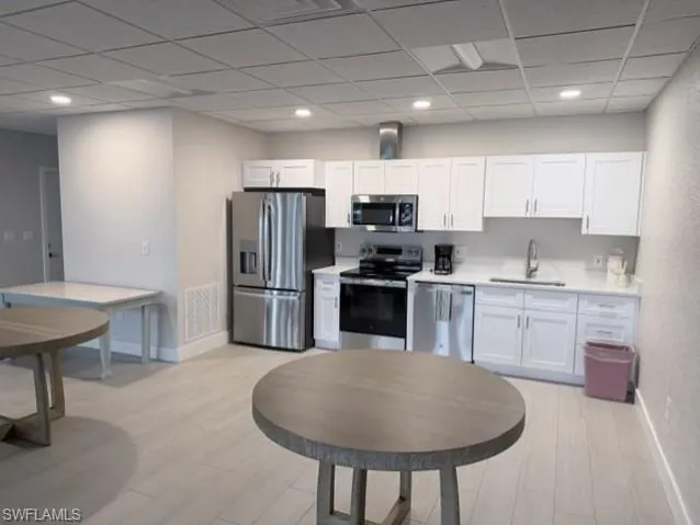 Kitchenette featuring white shaker cabinetry, stainless steel appliances, light countertops, and light wood-finish flooring
