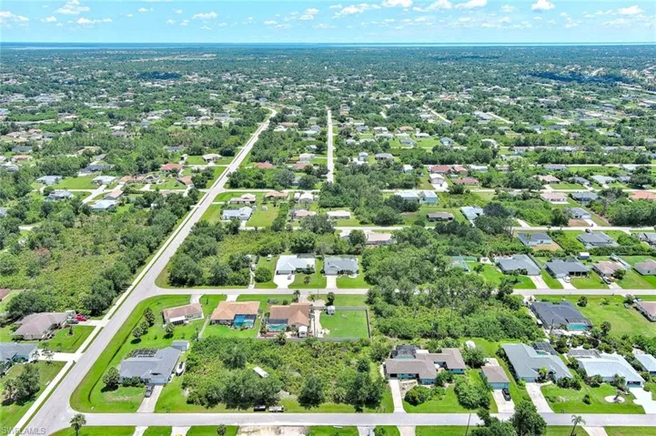 Aerial view of property's location featuring nearby suburban area and a tree filled landscape
