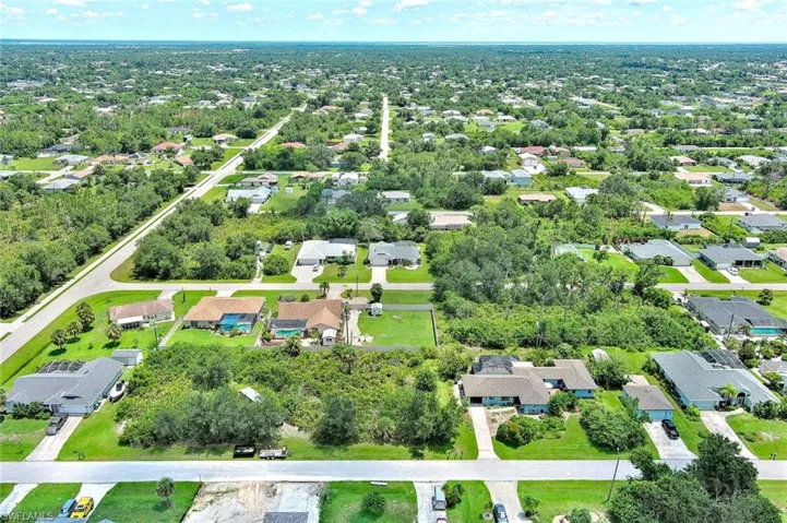 Aerial overview of property's location featuring nearby suburban area and a tree filled landscape