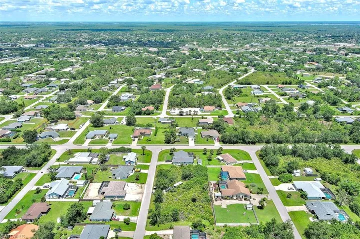 Aerial view of property and surrounding area with nearby suburban area and a tree filled landscape