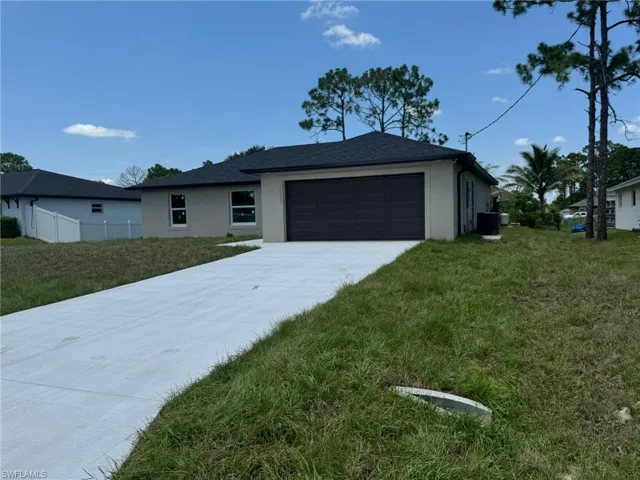 Ranch-style home featuring a garage, stucco siding, and concrete driveway