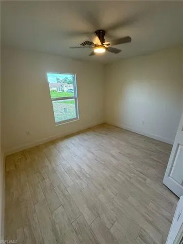Unfurnished guest bedroom featuring a ceiling fan, light wood-style flooring, and a textured ceiling