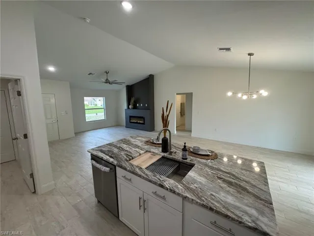 Unfurnished living room with a ceiling fan, a glass covered fireplace, a chandelier, light wood-style floors, and lofted ceiling