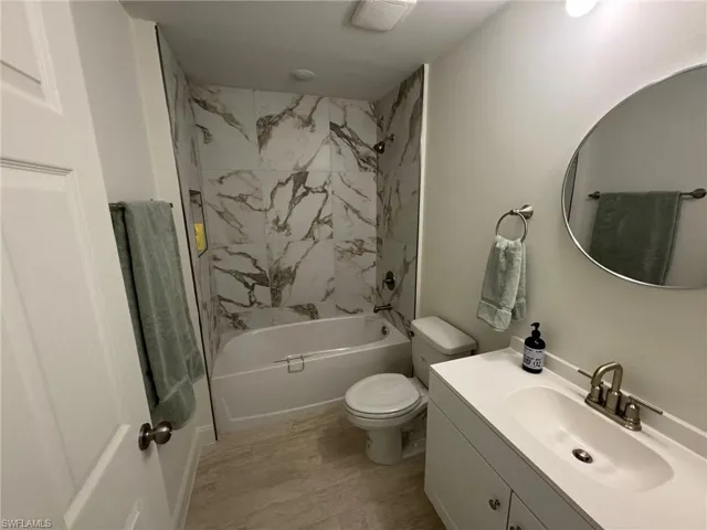 Bathroom featuring  shower combination, vanity, and wood finished floors