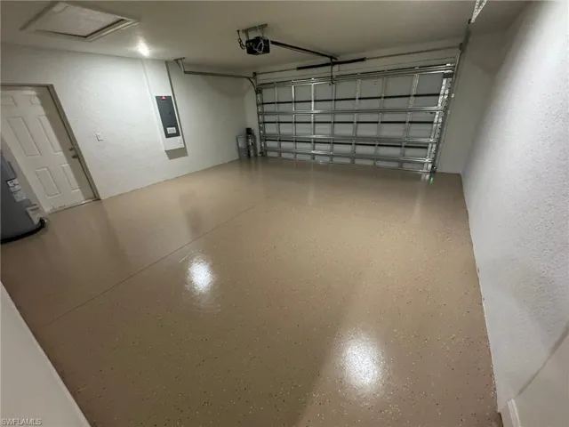 Garage featuring electric panel, a textured wall, and water heater