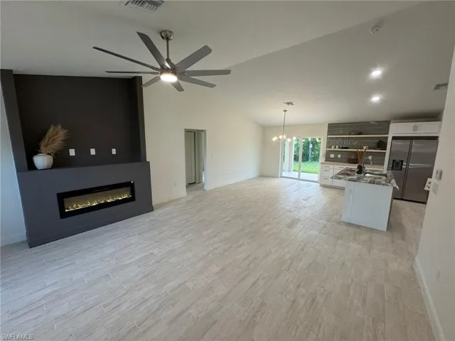 Unfurnished living room with a ceiling fan, vaulted ceiling, light wood finished floors, and recessed lighting