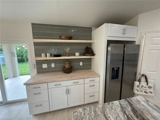 Kitchen featuring appliances with stainless steel finishes, decorative backsplash, light wood-type flooring, stone counters, and recessed lighting