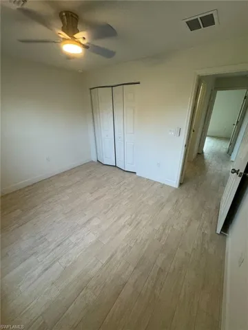 Unfurnished guest bedroom with light wood-style flooring, a closet, and ceiling fan