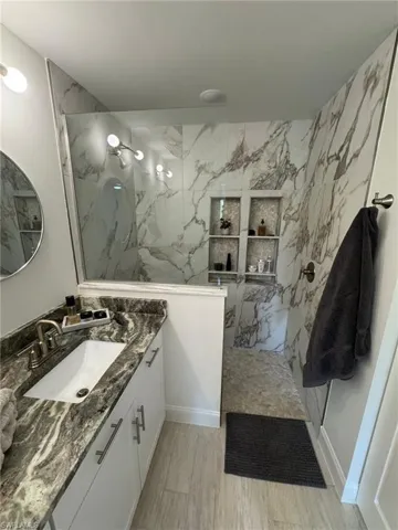 Bathroom featuring vanity and a marble finish shower