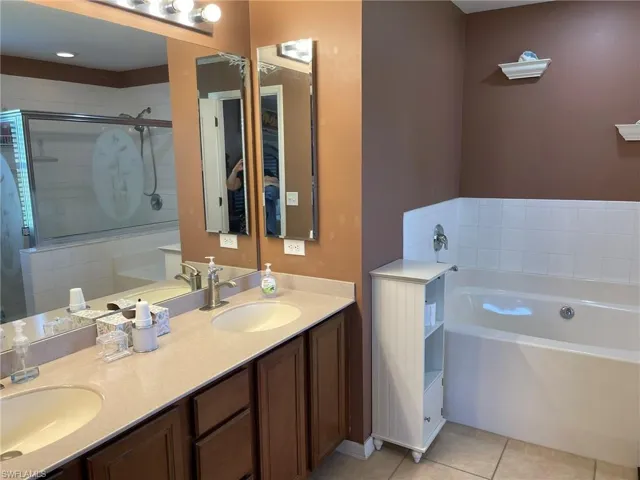 Bathroom featuring vanity, shower with separate bathtub, and tile patterned flooring
