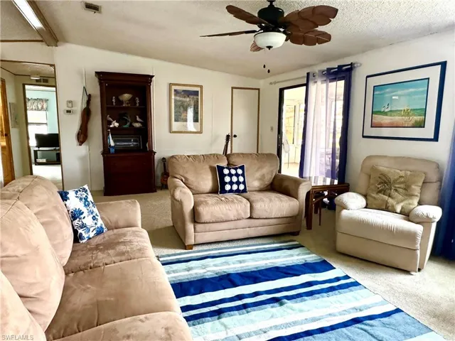 Living room, sliding doors leading to the lanai/sun room, and doorway to a guest room.