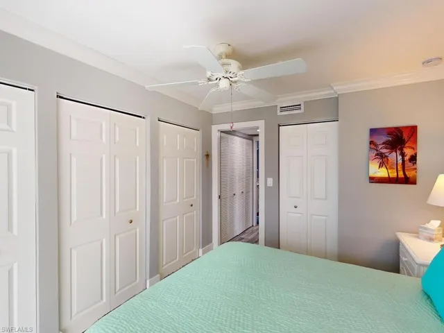 Bedroom featuring ornamental molding, ceiling fan, and multiple closets