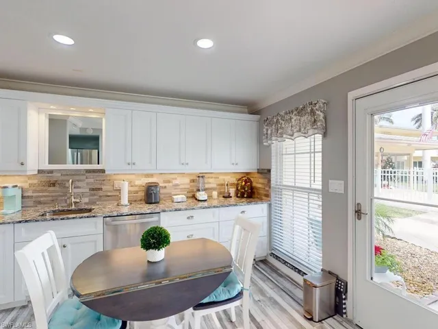 Kitchen with decorative backsplash, white cabinetry, dishwasher, and sink