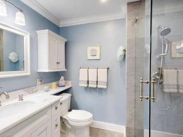 Bathroom featuring vanity, tile patterned floors, toilet, ornamental molding, and a shower with shower door