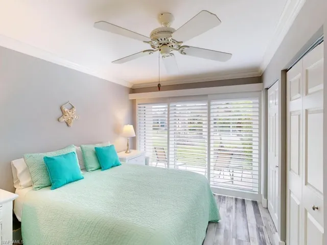 Bedroom with ceiling fan, crown molding, and light wood-type flooring