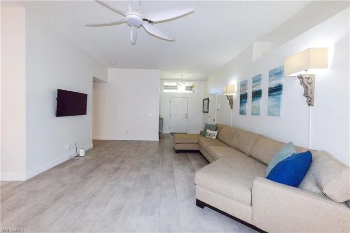 Living room with ceiling fan with notable chandelier and light hardwood / wood-style flooring