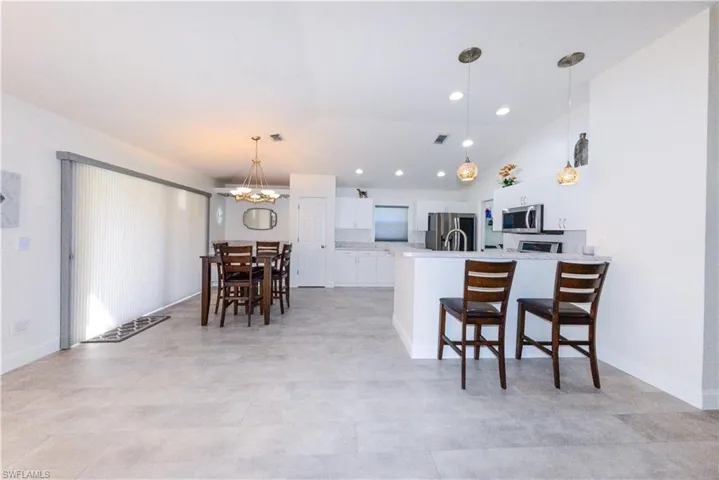 Kitchen with stainless steel appliances, lofted ceiling, kitchen peninsula, a breakfast bar area, and white cabinetry