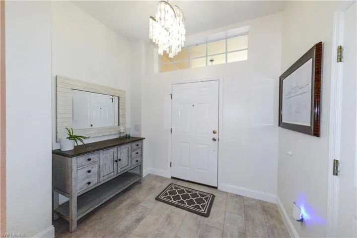 Entryway featuring light hardwood / wood-style floors, a high ceiling, and an inviting chandelier