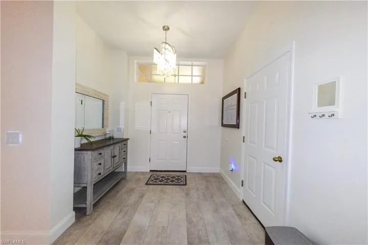 Entrance foyer with a chandelier, a towering ceiling, and light hardwood / wood-style flooring