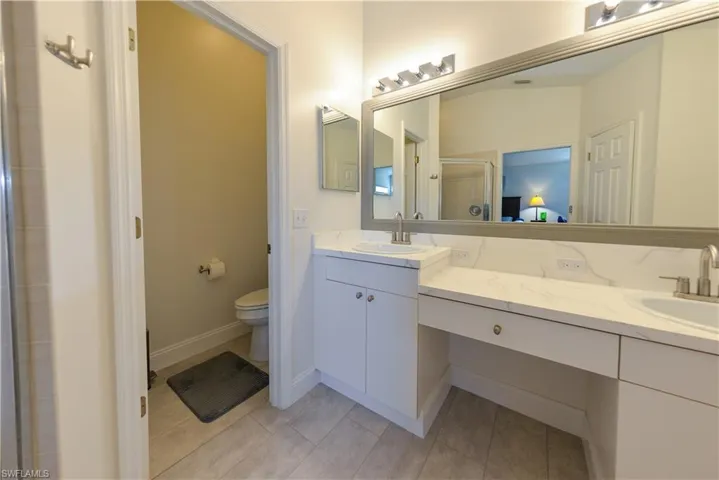 Bathroom featuring toilet, vanity, and a shower with door