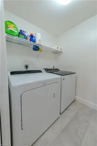 Laundry area featuring light tile patterned floors and washer and dryer