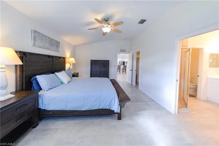 Bedroom with ceiling fan, ensuite bath, and vaulted ceiling
