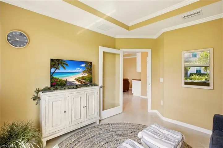 Den area with light tile patterned floors and ornamental molding