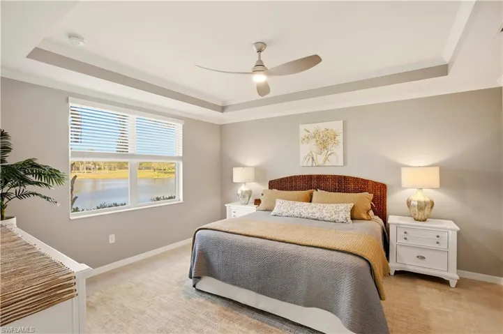 Bedroom featuring crown molding, a ceiling fan, a trayed ceiling, and a water view
