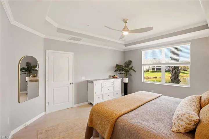 Bedroom featuring ceiling fan, ornamental molding, a tray ceiling, and light tile patterned floors