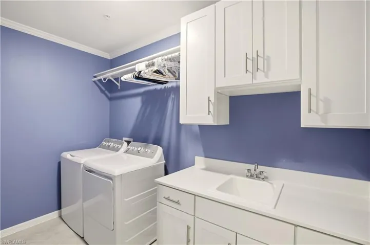 Laundry room featuring cabinet space, crown molding, and washer and clothes dryer