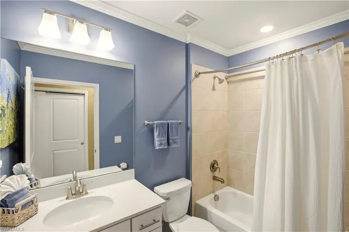 Bathroom featuring vanity, shower / bath combo with shower curtain, and ornamental molding